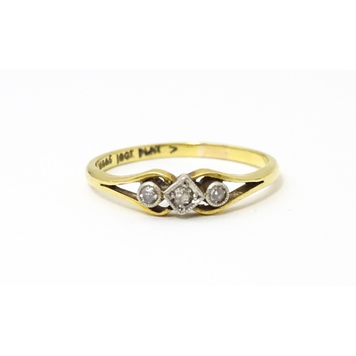 651 - An 18ct gold ring with platinum set central diamond flanked by two further diamonds. Ring size appro... 