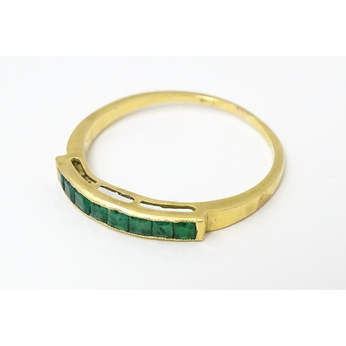 658 - A gold ring set with band of emeralds.  Ring size approx. Q