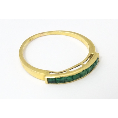 658 - A gold ring set with band of emeralds.  Ring size approx. Q