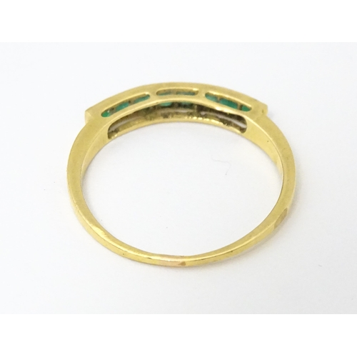 658 - A gold ring set with band of emeralds.  Ring size approx. Q