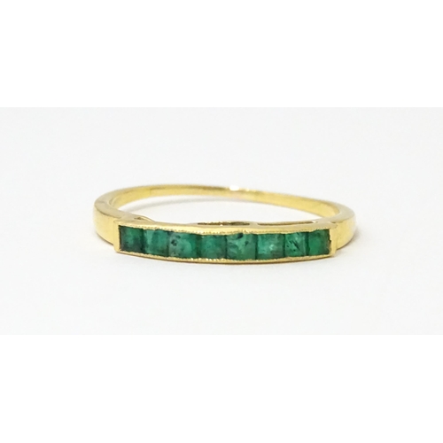 658 - A gold ring set with band of emeralds.  Ring size approx. Q