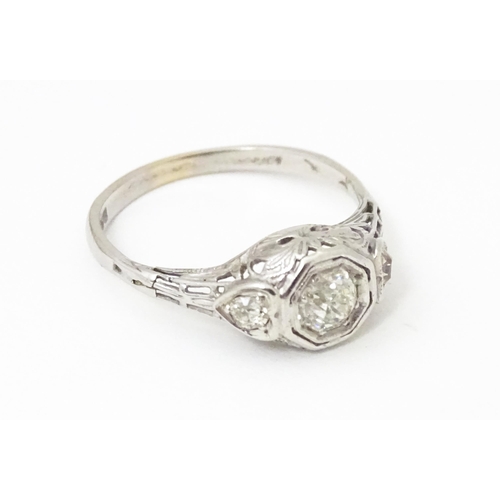 660 - An 18ct white gold ring with central diamond flanked by two further diamonds, in an Art deco style s... 