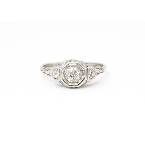 660 - An 18ct white gold ring with central diamond flanked by two further diamonds, in an Art deco style s... 