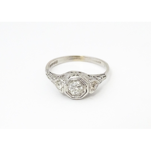 660 - An 18ct white gold ring with central diamond flanked by two further diamonds, in an Art deco style s... 