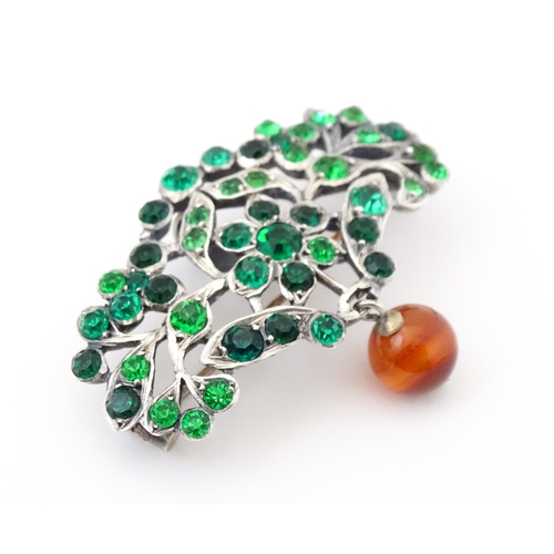 673 - A white metal brooch set with green paste stones and carnelian bead drop. Approx 2