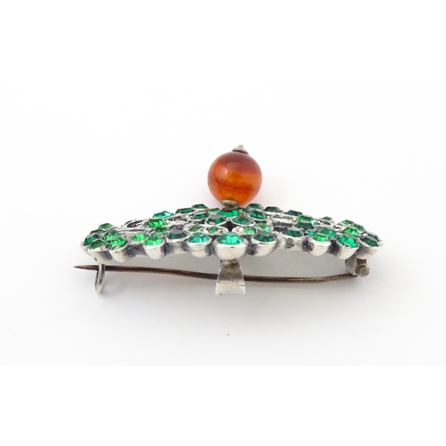 673 - A white metal brooch set with green paste stones and carnelian bead drop. Approx 2