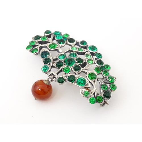 673 - A white metal brooch set with green paste stones and carnelian bead drop. Approx 2