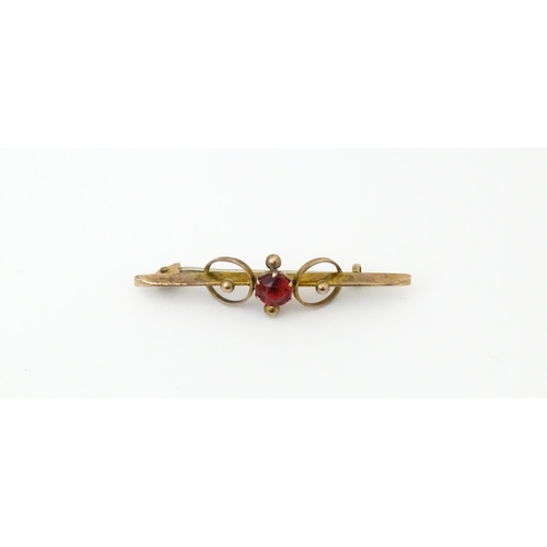 676 - A 9ct gold bar brooch set with red stone. 1 3/4