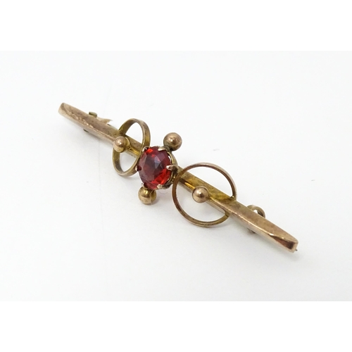 676 - A 9ct gold bar brooch set with red stone. 1 3/4