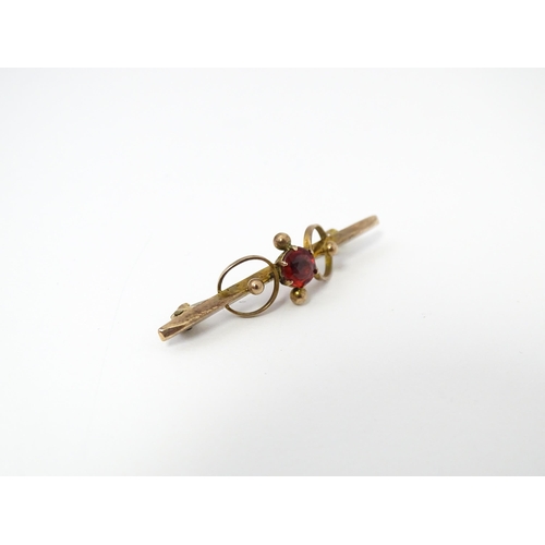 676 - A 9ct gold bar brooch set with red stone. 1 3/4