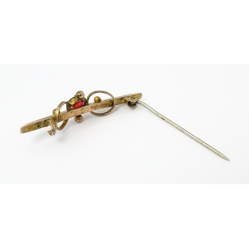 676 - A 9ct gold bar brooch set with red stone. 1 3/4