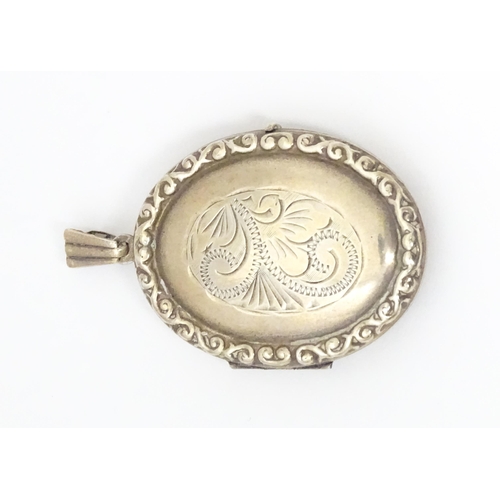 677 - A white metal pendant of locket form with engrave decoration. Approx 1 1/5