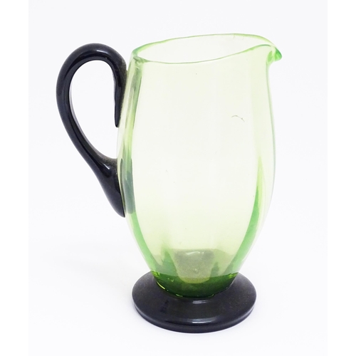 261 - An early 20thC Uranium glass  water jug / pitcher, the pale green body with darker green foot and ha... 