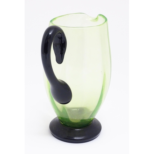 261 - An early 20thC Uranium glass  water jug / pitcher, the pale green body with darker green foot and ha... 