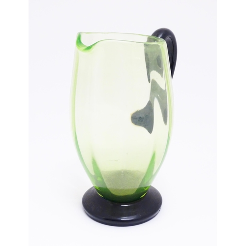 261 - An early 20thC Uranium glass  water jug / pitcher, the pale green body with darker green foot and ha... 