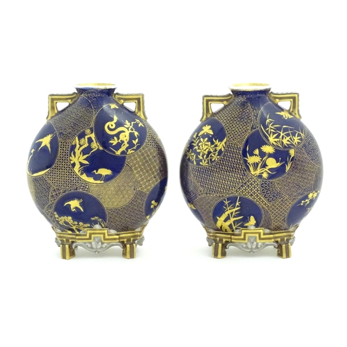 112 - Two Royal Worcester Aesthetic Movement moon flask vases with twin gilt handles and raised feet, the ... 