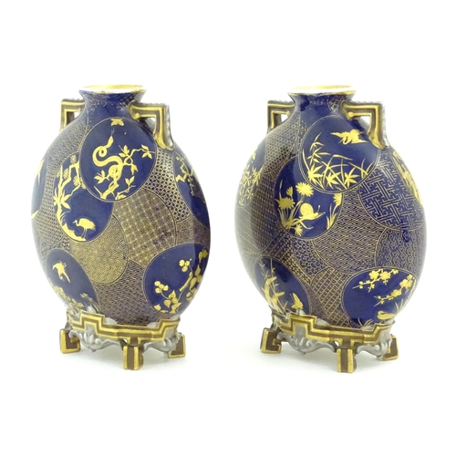 112 - Two Royal Worcester Aesthetic Movement moon flask vases with twin gilt handles and raised feet, the ... 