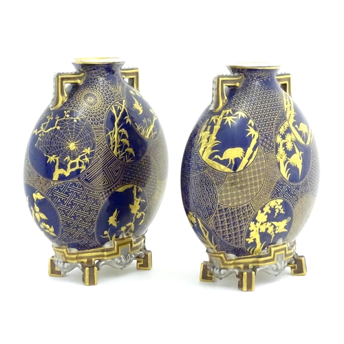 112 - Two Royal Worcester Aesthetic Movement moon flask vases with twin gilt handles and raised feet, the ... 