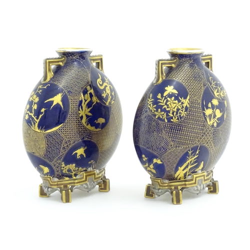 112 - Two Royal Worcester Aesthetic Movement moon flask vases with twin gilt handles and raised feet, the ... 