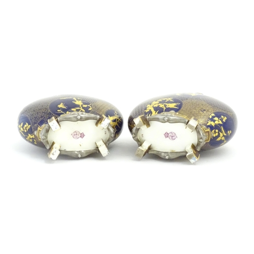 112 - Two Royal Worcester Aesthetic Movement moon flask vases with twin gilt handles and raised feet, the ... 