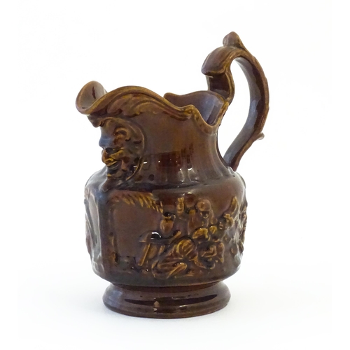 121 - A treacle glazed jug with monkey and mask detail. Approx. 6 1/2