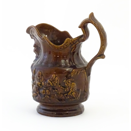 121 - A treacle glazed jug with monkey and mask detail. Approx. 6 1/2