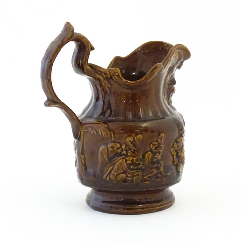 121 - A treacle glazed jug with monkey and mask detail. Approx. 6 1/2