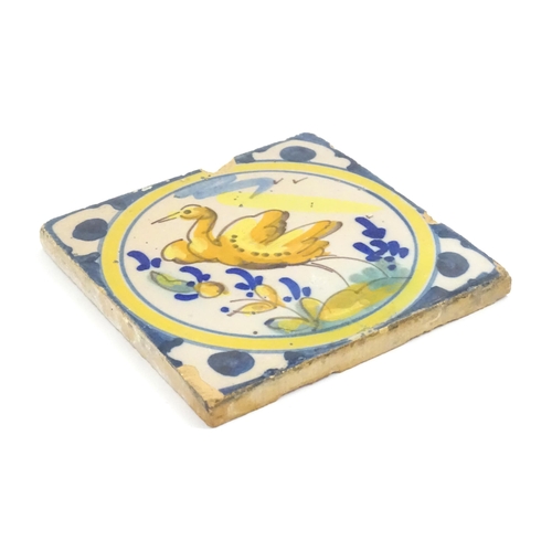 130 - A Continental Delft style tile depicting a bird within a roundel, with shaped detail to corners. App... 