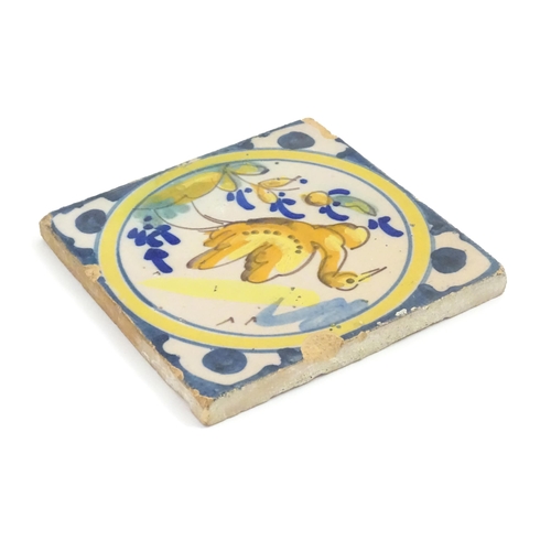 130 - A Continental Delft style tile depicting a bird within a roundel, with shaped detail to corners. App... 