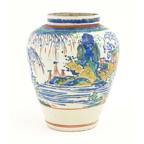 41 - A Japanese Kakiemon style jar / vase of ovoid form decorated with a lake scene with small buildings ... 