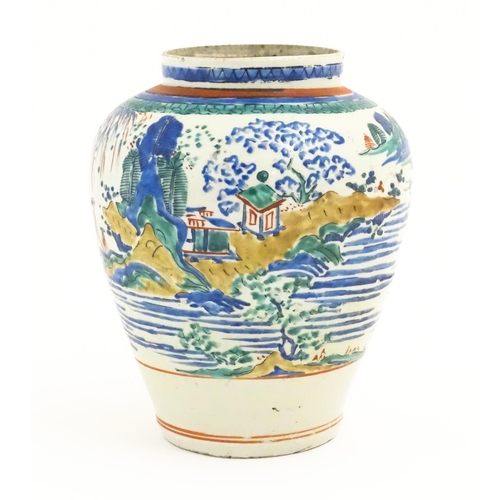 41 - A Japanese Kakiemon style jar / vase of ovoid form decorated with a lake scene with small buildings ... 
