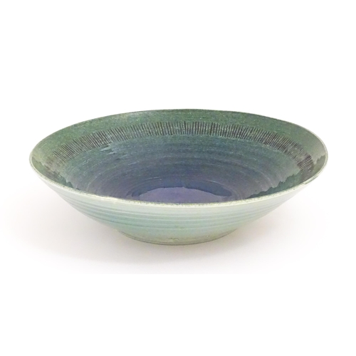 95 - A studio pottery bowl by Mike / Michael Dixon with blue / green glaze and incised banded detail to i... 