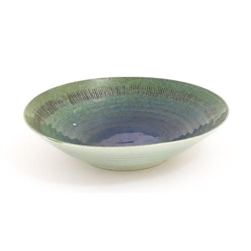 95 - A studio pottery bowl by Mike / Michael Dixon with blue / green glaze and incised banded detail to i... 