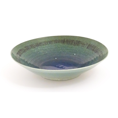 95 - A studio pottery bowl by Mike / Michael Dixon with blue / green glaze and incised banded detail to i... 