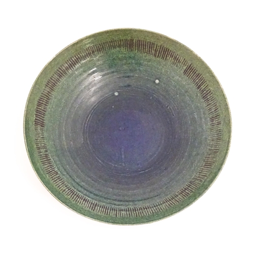 95 - A studio pottery bowl by Mike / Michael Dixon with blue / green glaze and incised banded detail to i... 