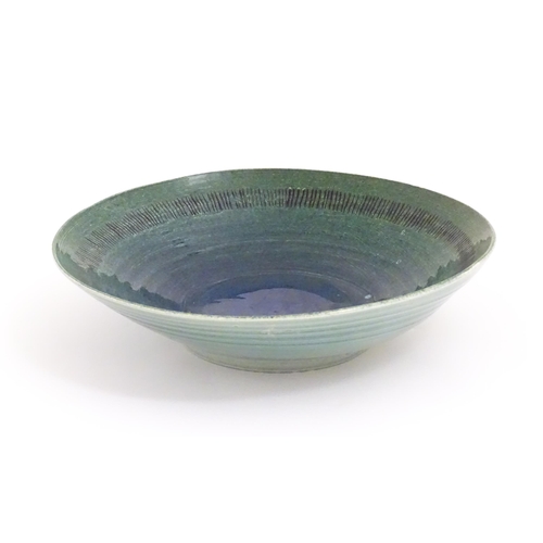 95 - A studio pottery bowl by Mike / Michael Dixon with blue / green glaze and incised banded detail to i... 