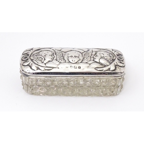 337 - A cut glass dressing table pot with embossed silver lid with cherub / angel decoration, hallmarked B... 