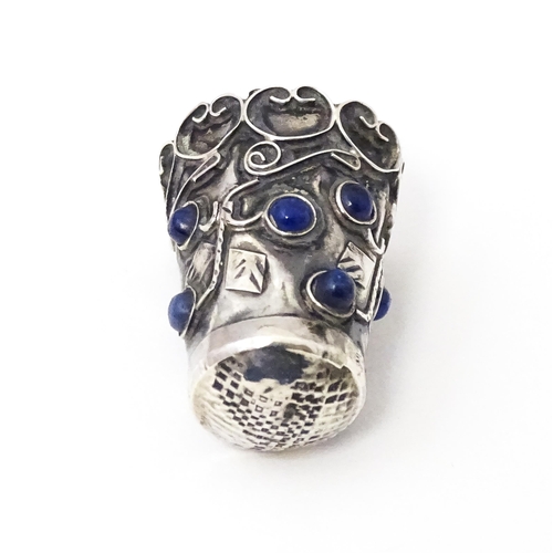 374 - A white metal thimble with blue cabochon detail. 1