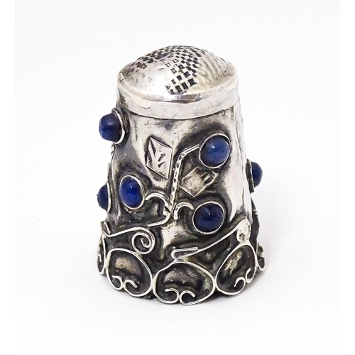 374 - A white metal thimble with blue cabochon detail. 1