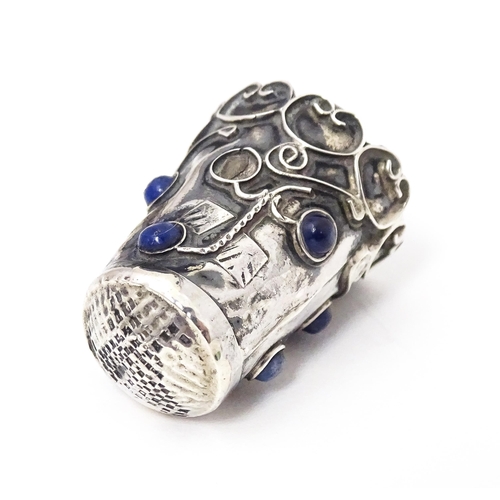 374 - A white metal thimble with blue cabochon detail. 1