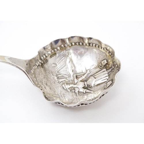 390 - A Dutch silver caddy spoon with landscape scene with figure, windmill etc to bowl and scroll, figure... 