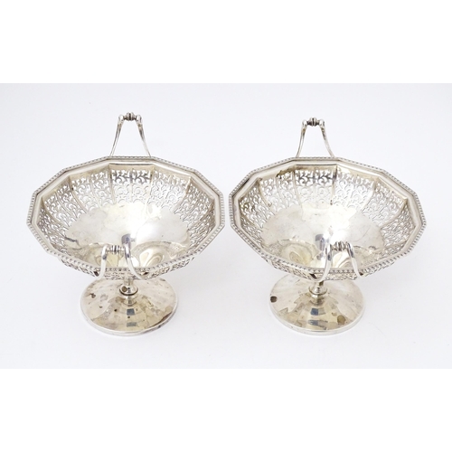 444 - A pair of silver bon bon dished of pedestal form with pierced decoration and twin handles. Hallmarke... 