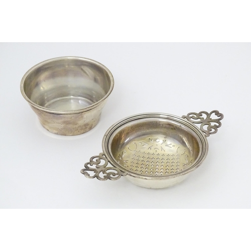 471 - A silver twin handled lemon / tea strainer with pierced detail and bowl under. Hallmarked Birmingham... 