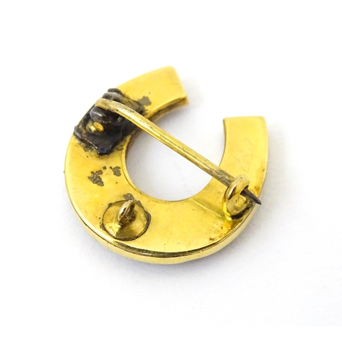 686 - A yellow metal brooch of horseshoe form set with cats eye cabochon and seed pearls. 3 3/4