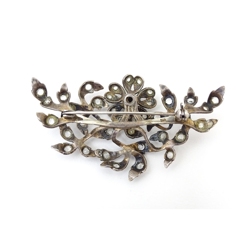 692 - A white metal brooch  of floral and foliate form set with paste detail. Approx 3