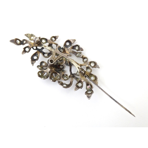 692 - A white metal brooch  of floral and foliate form set with paste detail. Approx 3