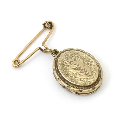 695 - A yellow metal pendant locket with engraved decoration suspended from a 9ct gold brooch hanger hallm... 