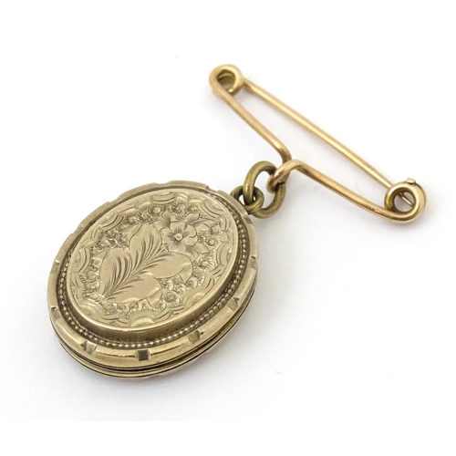 695 - A yellow metal pendant locket with engraved decoration suspended from a 9ct gold brooch hanger hallm... 