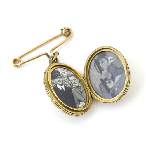 695 - A yellow metal pendant locket with engraved decoration suspended from a 9ct gold brooch hanger hallm... 