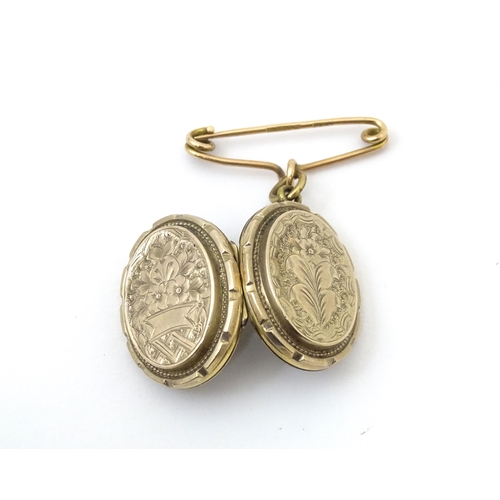 695 - A yellow metal pendant locket with engraved decoration suspended from a 9ct gold brooch hanger hallm... 